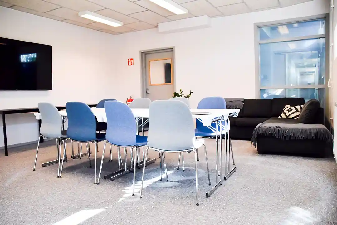 Himledalen möblerad med konferensbord, blå och grå stolar, skärm på väggen och soffhörna